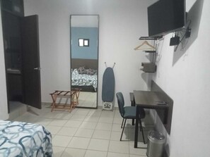 A compact hotel room with a bed, a desk, a chair, a TV, and a wardrobe. - MONARCA HOTEL & PLAZA  (Atlacomulco)