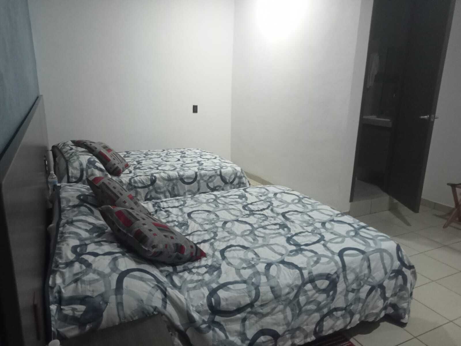 A small, simple room with a bed, a chair, and a door.