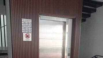 Een lift met een bordje waarop staat verboden te roken en mobiele telefoons te gebruiken.