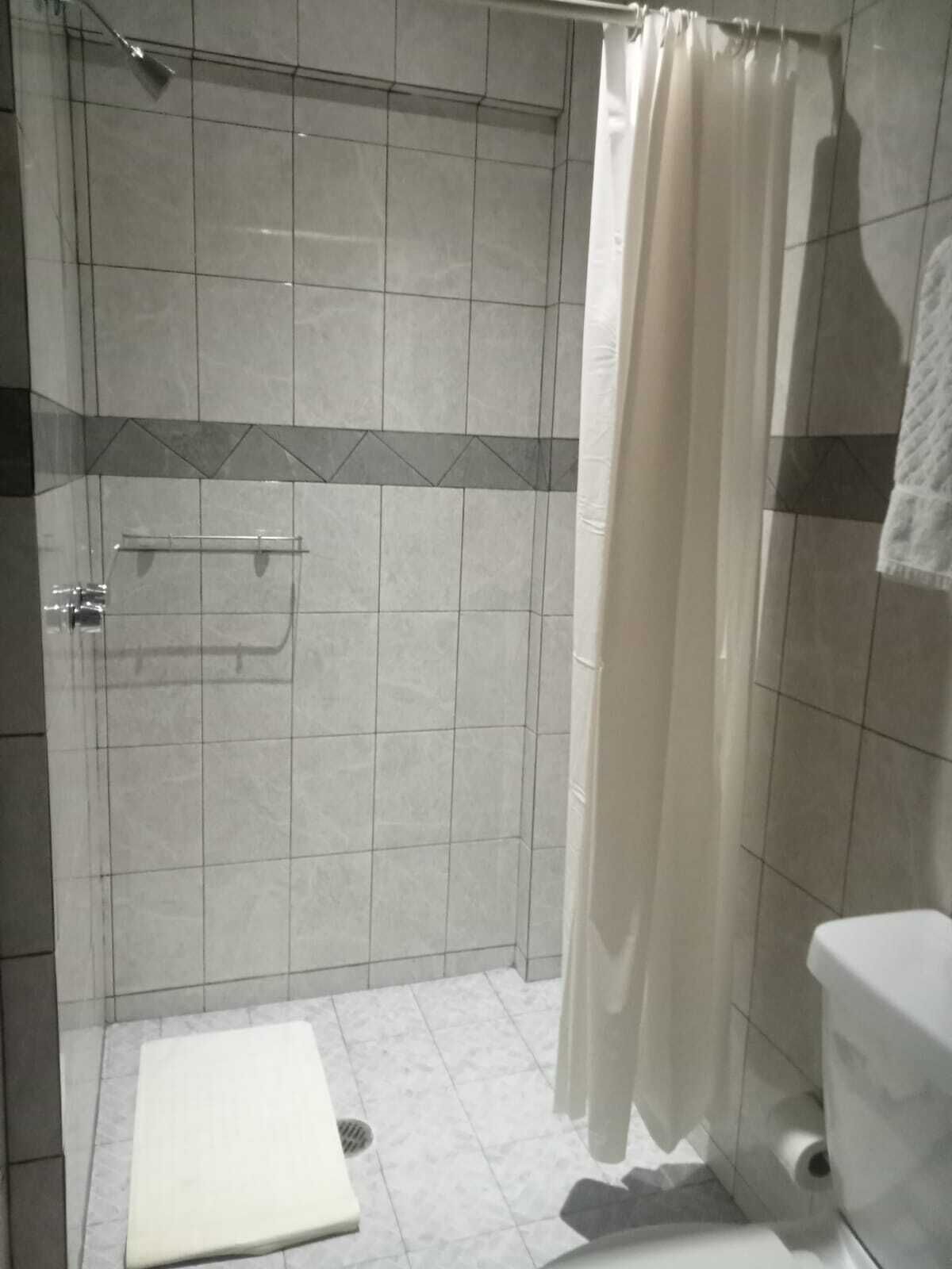 A bathroom with a shower, toilet, and a towel rack.