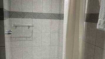 A bathroom with a shower, toilet, and a towel rack.