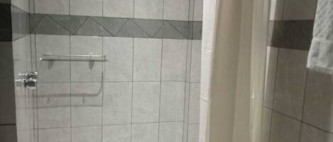 A bathroom with a shower, toilet, and a towel rack.