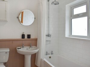 Un baño con lavamanos blanco, inodoro, ducha con puerta de cristal y ventana.