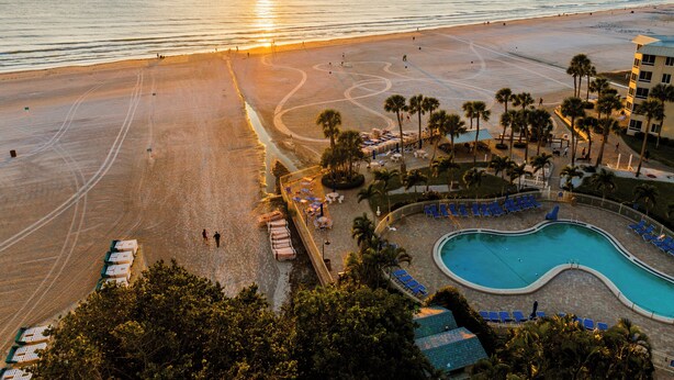 Ein Strandresort mit Swimmingpool, Strand und Palmen.