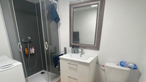 A modern bathroom with a glass shower enclosure, a white sink, a mirror, and a toilet. - Club House Dans Mini Ferme Danimation et Refuge (Courlans)