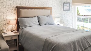Ein Schlafzimmer mit Bett, Nachttischen, einer Lampe und einem Fenster mit Blick.