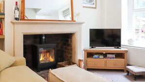 Ein Wohnzimmer mit Kamin, einem Fernseher auf einem Holzständer und einem großen Spiegel darüber.