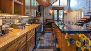 A modern kitchen with wooden cabinets, a stainless steel refrigerator, and a large island with a sink. - Historic Biloxi Beach House (Biloxi)