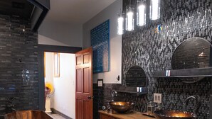 A modern kitchen with dark tiled backsplash, wooden cabinets, and two large sinks. - Historic Biloxi Beach House (Biloxi)