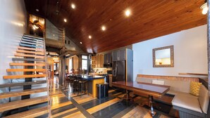 A modern kitchen with a central island, wooden staircase, and a dining area with a bench. - Historic Biloxi Beach House (Biloxi)