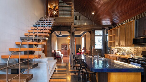 A modern kitchen with a central island, wooden staircase, and a cozy seating area. - Historic Biloxi Beach House (Biloxi)