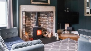 Una sala de estar acogedora con chimenea de piedra, un sofá cómodo y un televisor de pantalla plana montado en la pared.