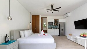 A modern hotel room with a bed, bedside table, and a TV. - Central Park Tulum G104 (Tulum)