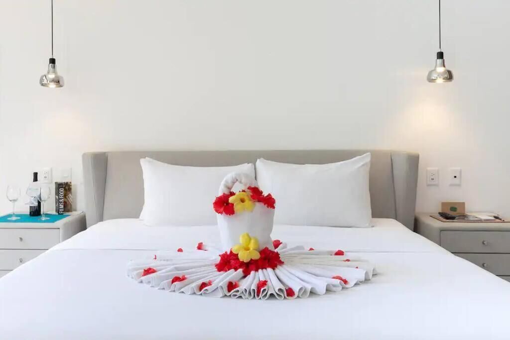 A neatly made bed with a decorative towel centerpiece, two bedside tables, and hanging light fixtures.