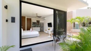 A modern hotel room with a sliding glass door leading to a balcony with outdoor seating. - Central Park Tulum G104 (Tulum)