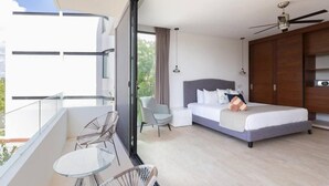 A modern hotel room with a balcony, a bed, a seating area, and a ceiling fan.