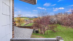 A view from a balcony overlooking a grassy area with trees and a distant landscape. - The Hideaway | 3 RV Hookups | Sleeps 17+ (Garden City)
