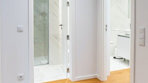 Un intérieur moderne avec un plancher en bois, des murs blancs et une cabine de douche en verre.