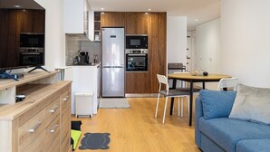 Une cuisine moderne équipée d’un réfrigérateur, d’un four à micro-ondes et d’un four traditionnel. On y trouve également un coin repas avec une table et des chaises, ainsi qu’un canapé bleu.