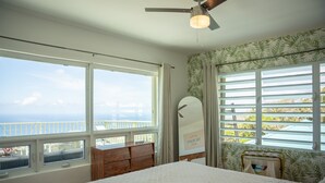 A bedroom with a large bed, a ceiling fan, and a view of the ocean through large windows. - The best views on St. Thomas,  pool, Jeep rental (St. Thomas)