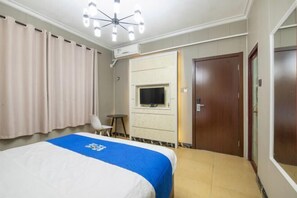 Une chambre d’hôtel avec un lit, une télévision, un bureau et une porte.