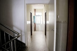 A hallway with a tiled floor, a wooden door on the right, and a staircase on the left. - Lanfeng Hotel (Sanya)