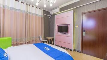 A hotel room with a bed, a television mounted on the wall, a small table, and a door.