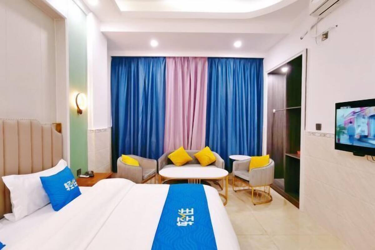 A hotel room with a bed, a TV, a sofa, and a small table.