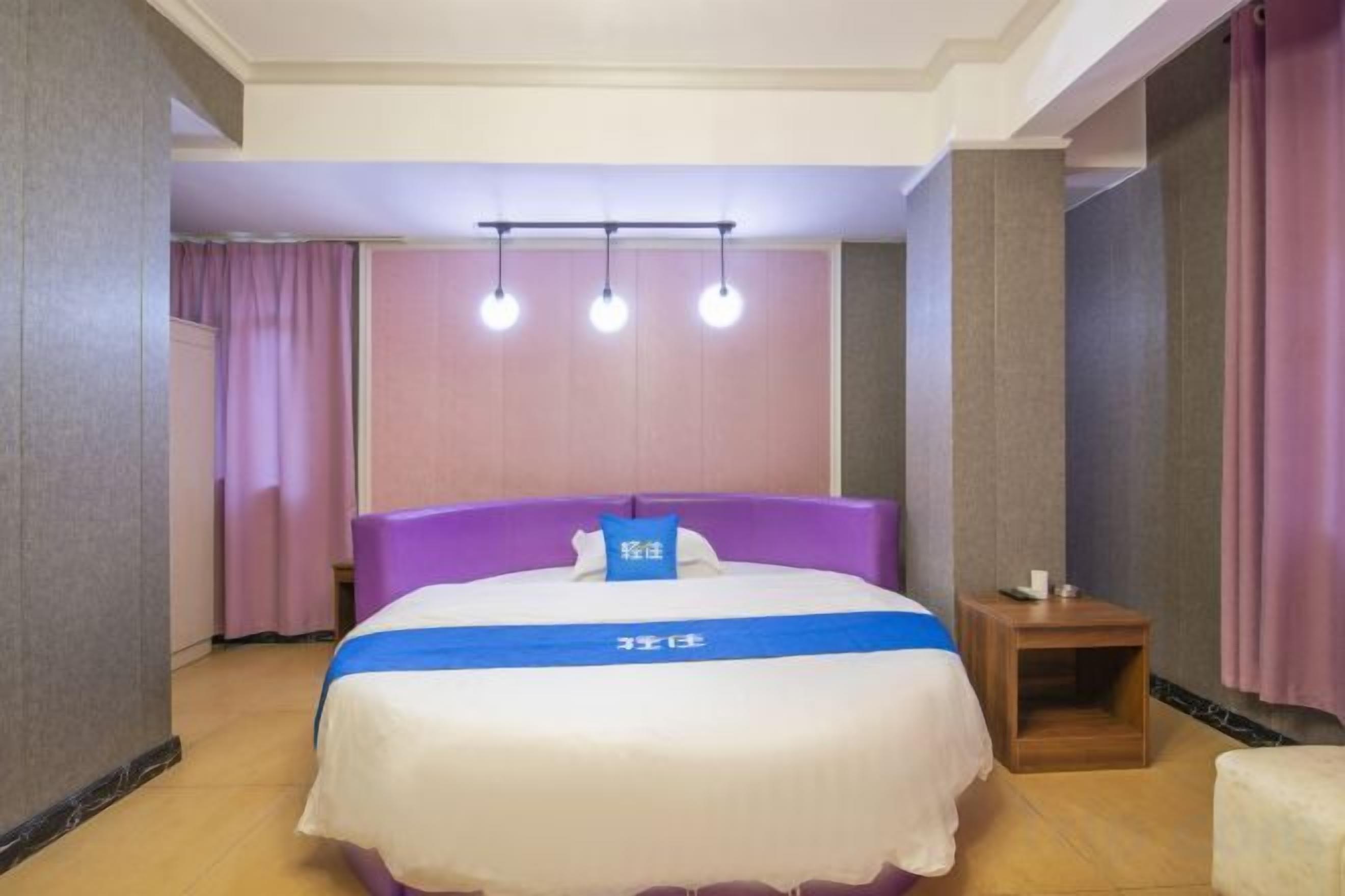 A hotel room with a bed, a bedside table, and a small nightstand.