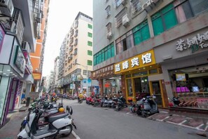 A street with parked scooters and a building with a yellow sign. - Lanfeng Hotel (Sanya)