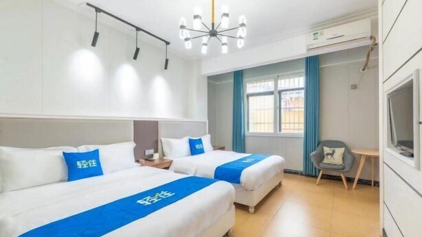 Ett hotellrum med två sängar, en TV, en stol och ett fönster med gardiner.