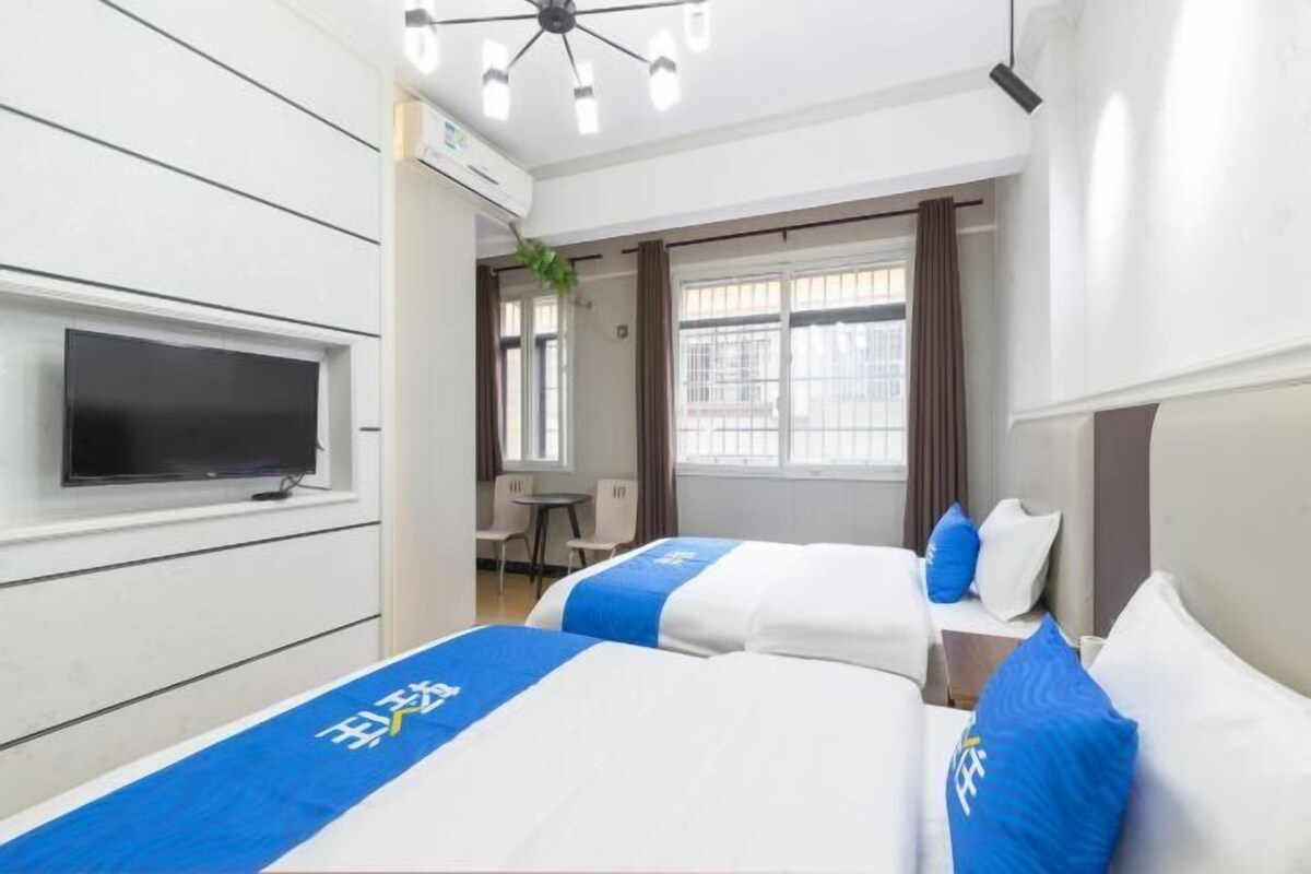 Une chambre d’hôtel avec deux lits, un téléviseur à écran plat, un bureau et une fenêtre avec des rideaux.