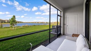 A modern room with a large window offering a view of a lake and grassy area.