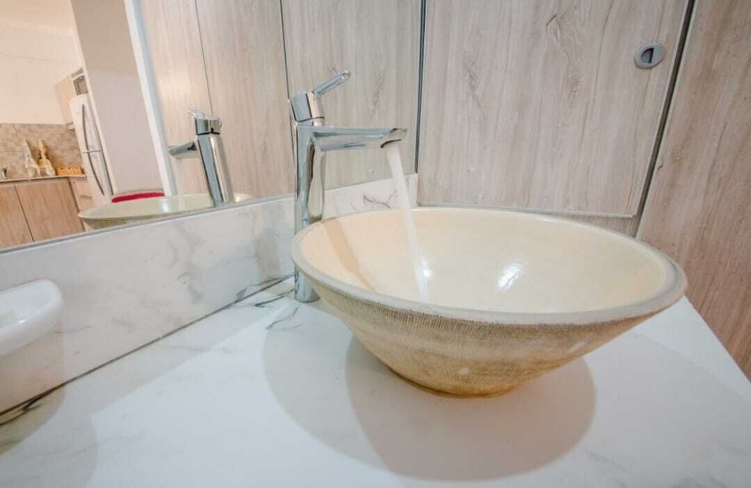 Une salle de bain avec un grand lavabo rond en céramique de couleur beige et un robinet moderne.