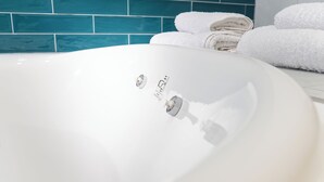 A white bathroom sink with a faucet, a towel rack with folded towels, and a blue-tiled wall.