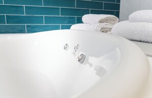 A white bathroom sink with a faucet, a towel rack with folded towels, and a blue-tiled wall.