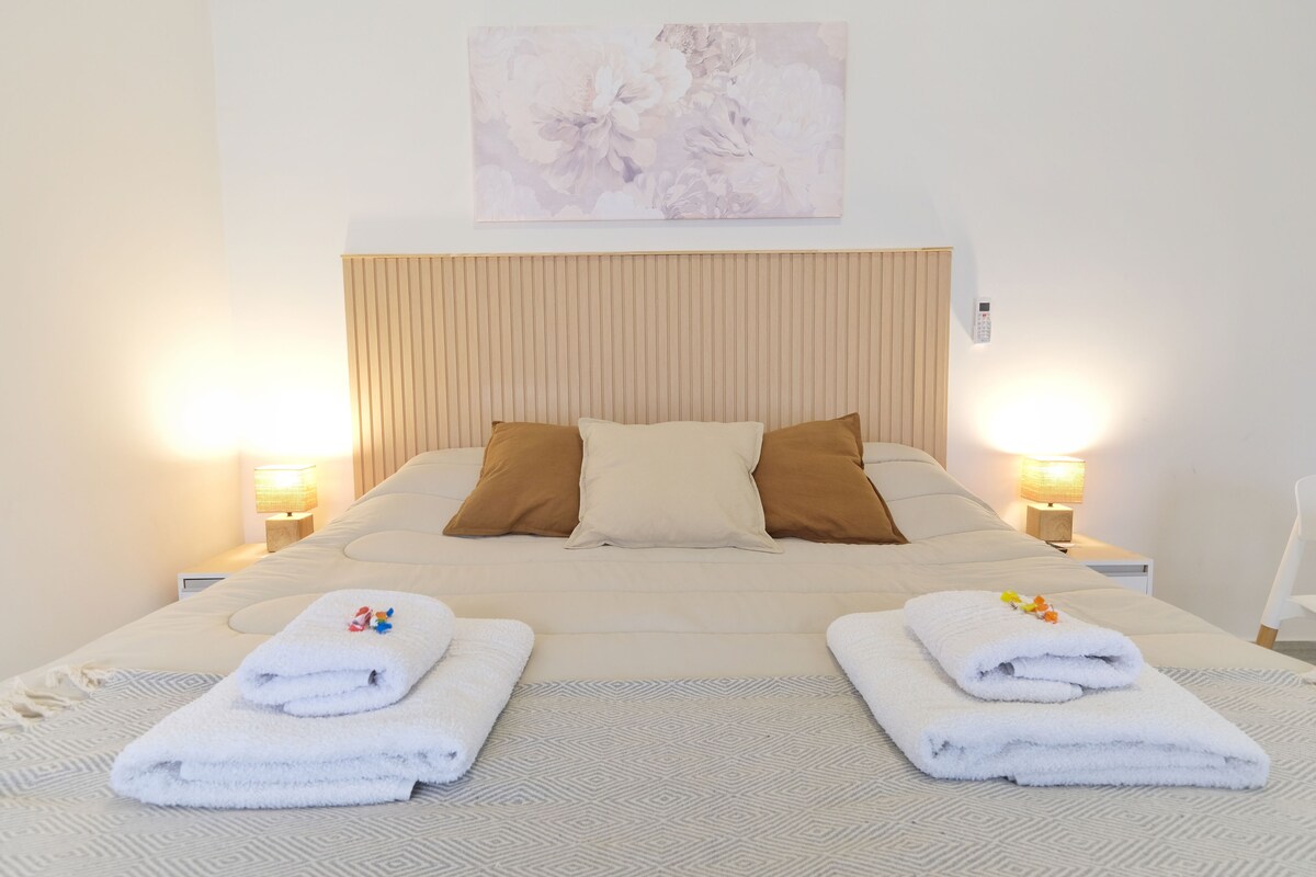 A hotel room with a large bed, two bedside lamps, a headboard, and a wall-mounted artwork.