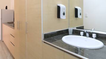 Un baño moderno con un espejo grande, un lavabo y un dispensador de jabón para manos.