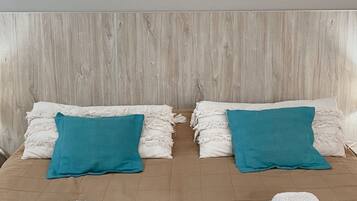 A double bed with two pillows, a wooden headboard, and two folded towels on the bed.