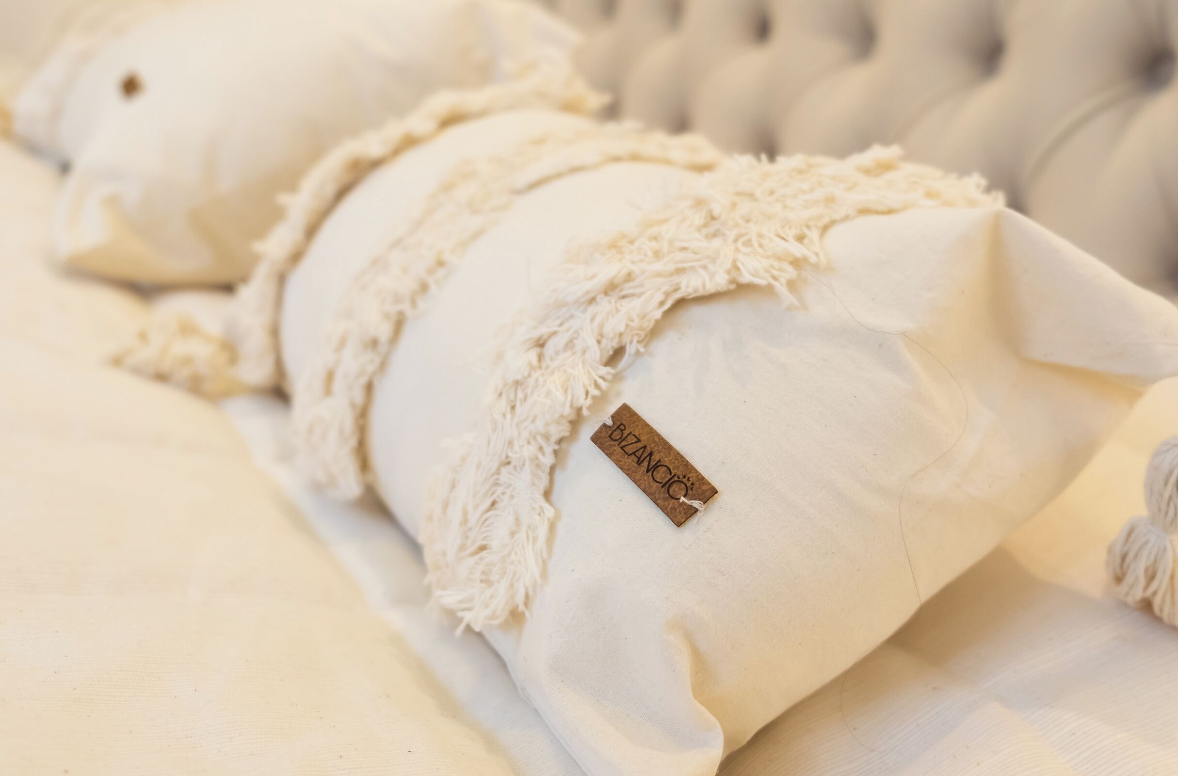 A plush, white, textured pillow with a tag labeled "BIZANO".