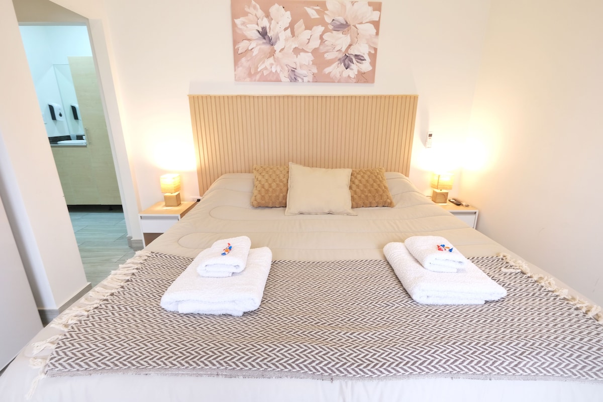 A neatly made bed with two pillows, a patterned rug, and two bedside lamps.