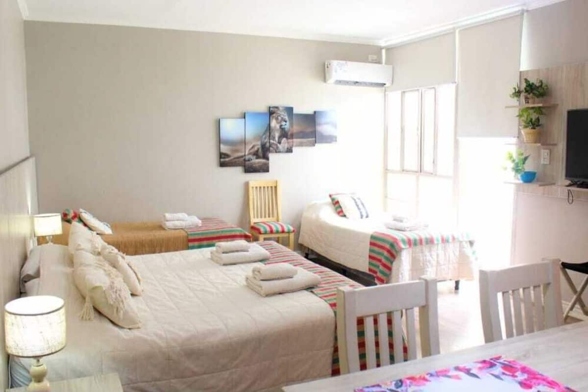 A hotel room with two beds, a TV, a desk, and a window.