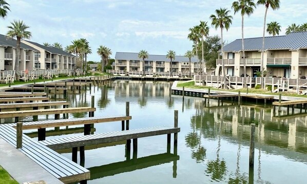 A waterfront hotel with multiple buildings, docked boats, and palm trees.