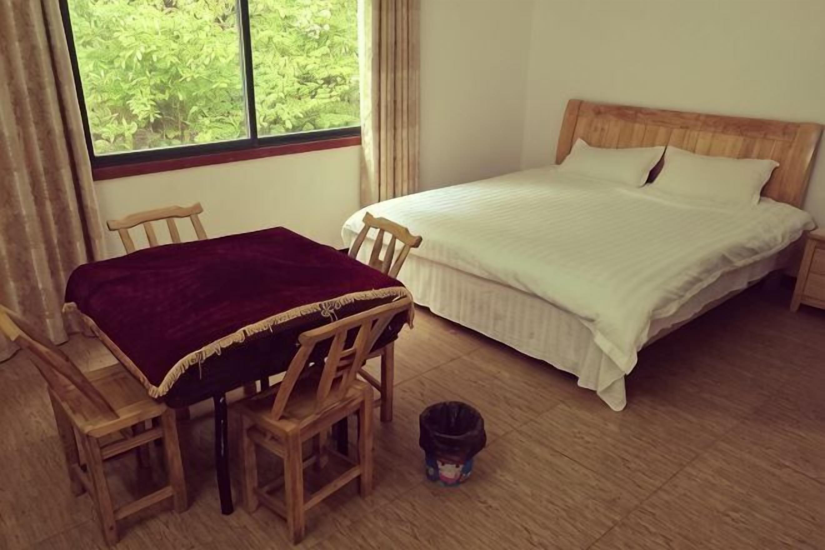Ein Schlafzimmer mit einem Bett, einem Tisch mit Stühlen, einem Fenster und Holzboden.
