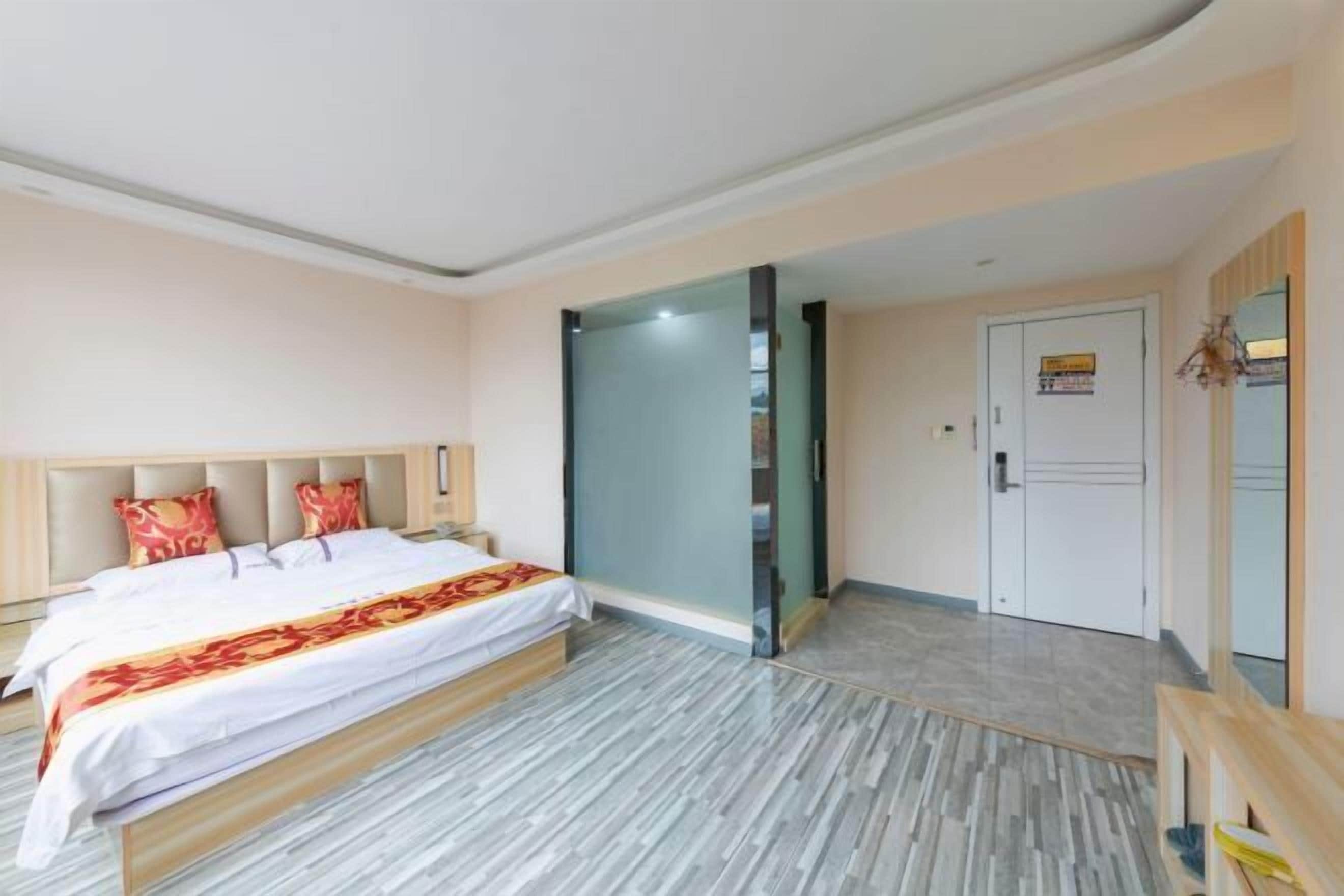 A hotel room with a large bed, a wooden headboard, a nightstand, and a mirror.