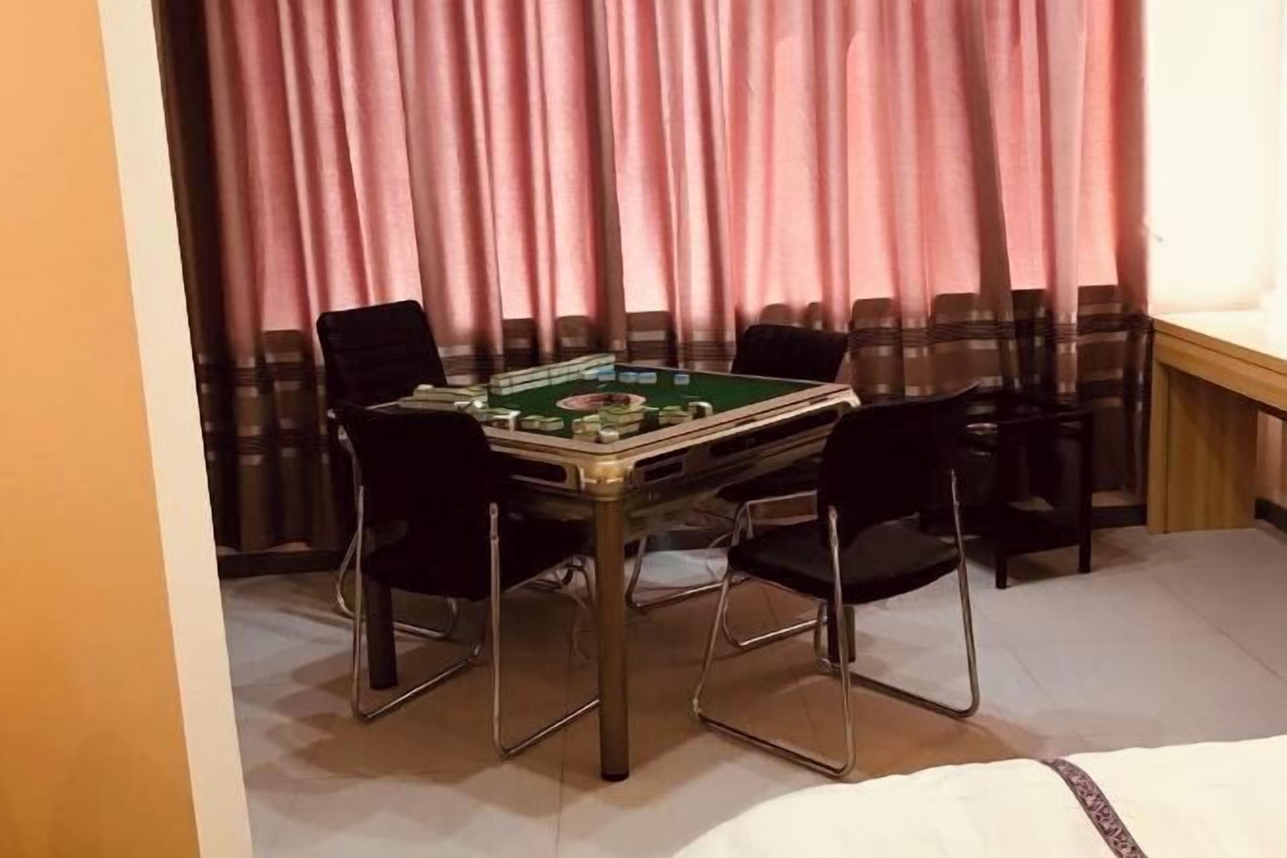 A room with a green pool table, four black chairs, and pink curtains.