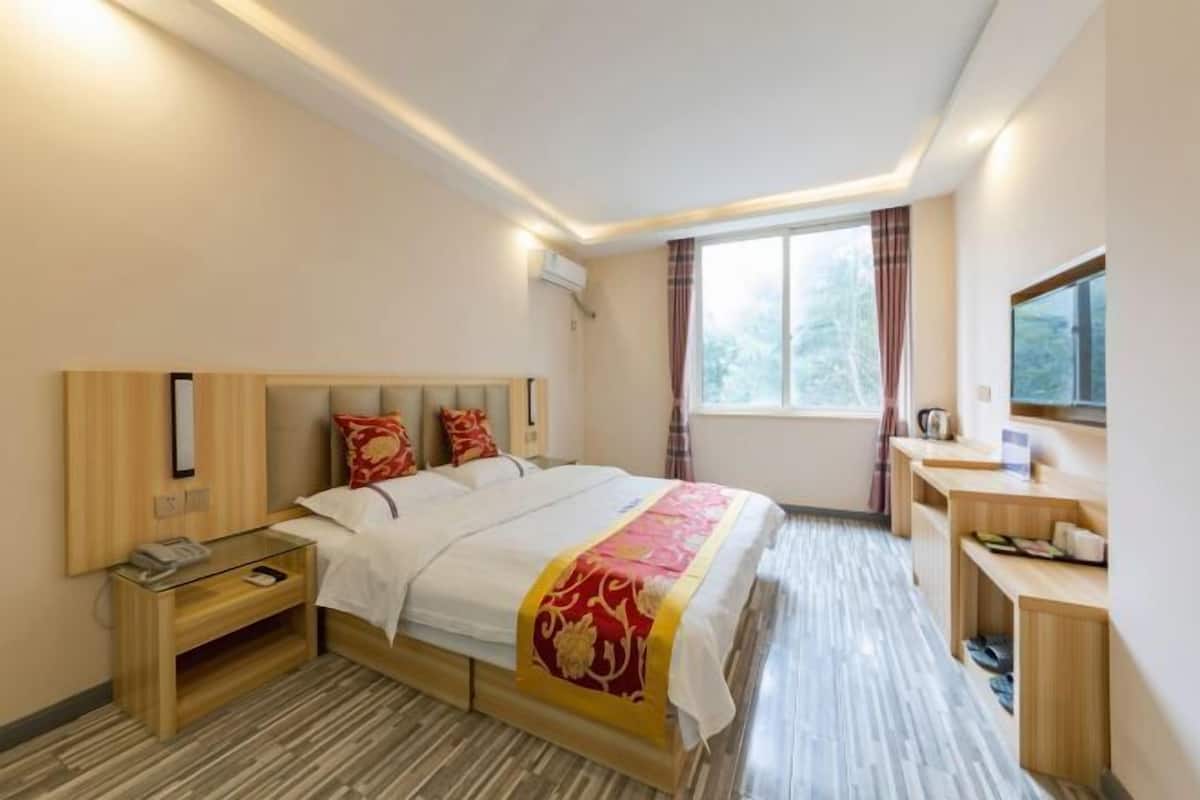 A hotel room with a bed, bedside table, and a window with curtains.