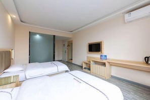 A hotel room with two beds, a TV, a coffee machine, and a small desk.