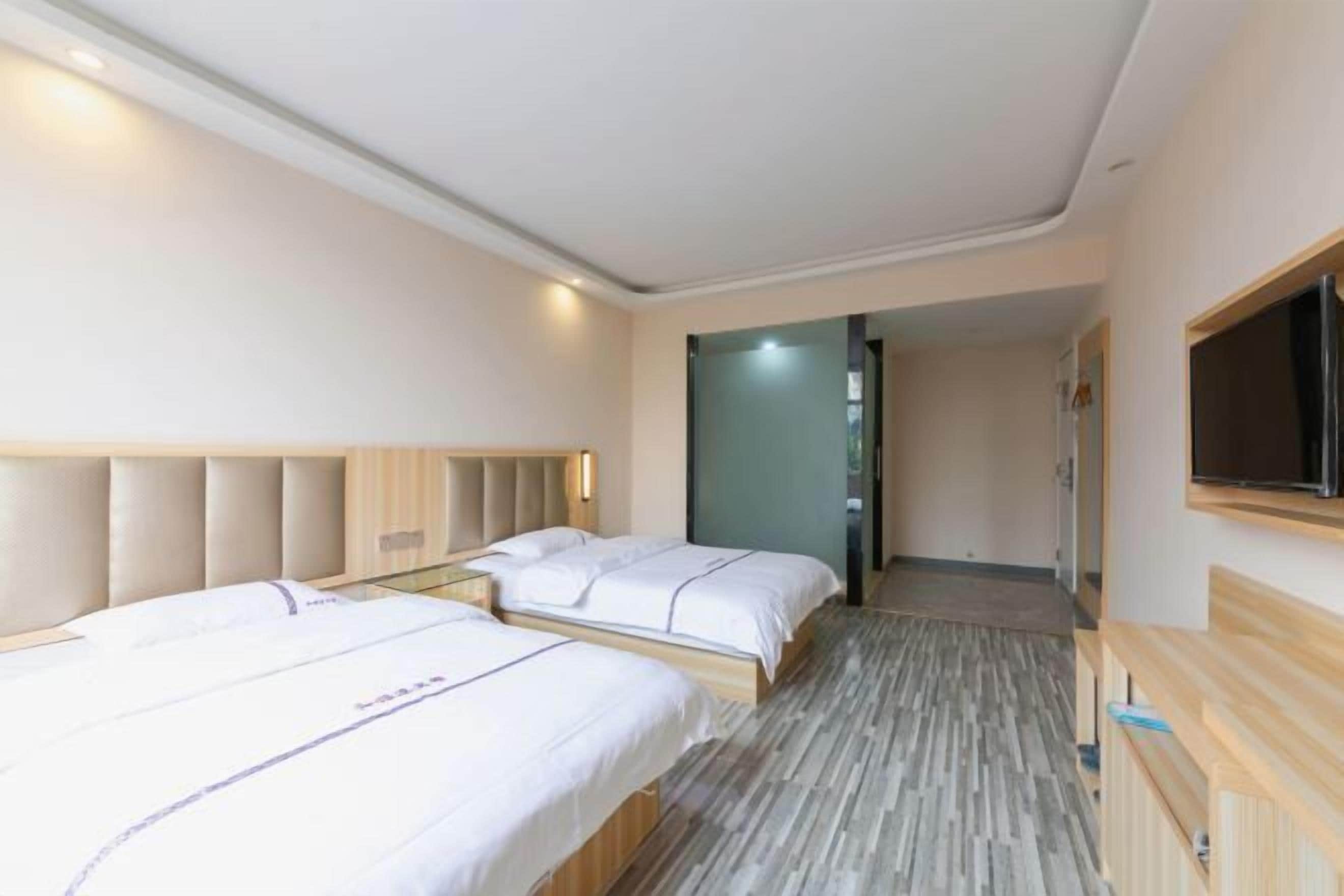 Een hotelkamer met twee bedden, een houten hoofdeinde, een flatscreen televisie en een houten bankje.
