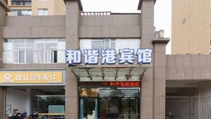 A hotel entrance with a signboard, a parking area, and a gated driveway. - Harmony Harbour Hotel (Sixin Avenue Subway Station Hancheng Garden ) (Wuhan)